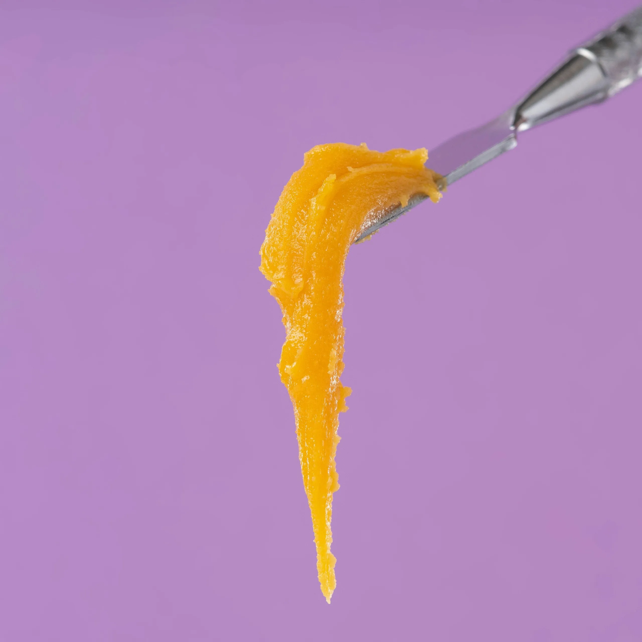 Bernsteinfarbenes Cannabisextrakt zieht Fäden von einem Metallwerkzeug