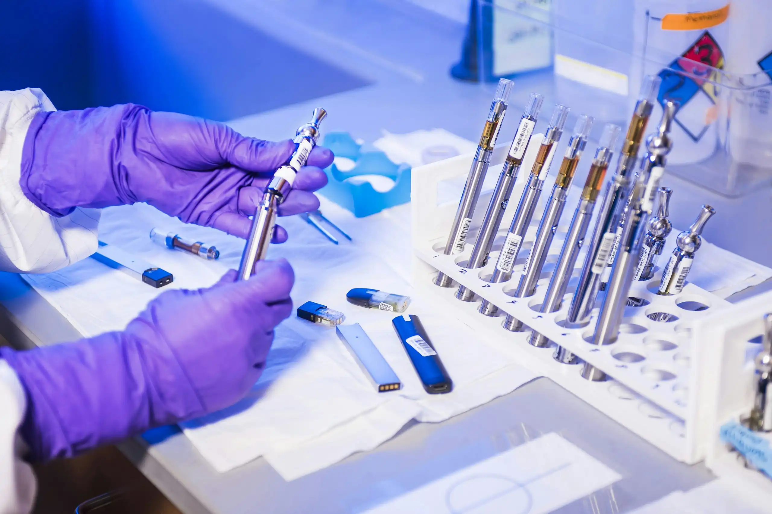 Hände in violetten Laborhandschuhen prüfen Proben an einem Analyseplatz